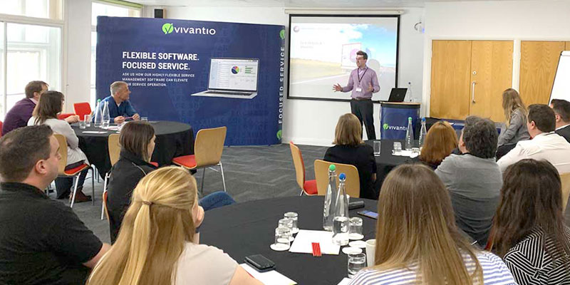 a business casual man presents vivantio information at the front of a room of software users